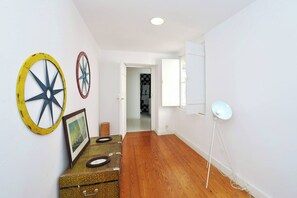 A hallway with a wooden floor, a vintage suitcase, and wall decorations including a wheel.