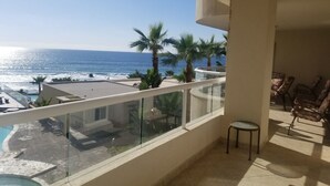A balcony with a view of the ocean, a pool, and palm trees. - !!!!!!  LA JOLLA DEL MAR ROSARITO SHORES. !!!!! (Playas Rosarito)