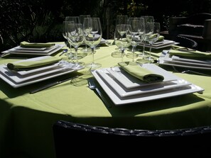 A round table set for a meal with multiple wine glasses, plates, and folded napkins. - Comfortable, quiet, spacious apartment, lush garden, Nice hinterland  (Roquefort-Les-Pins)