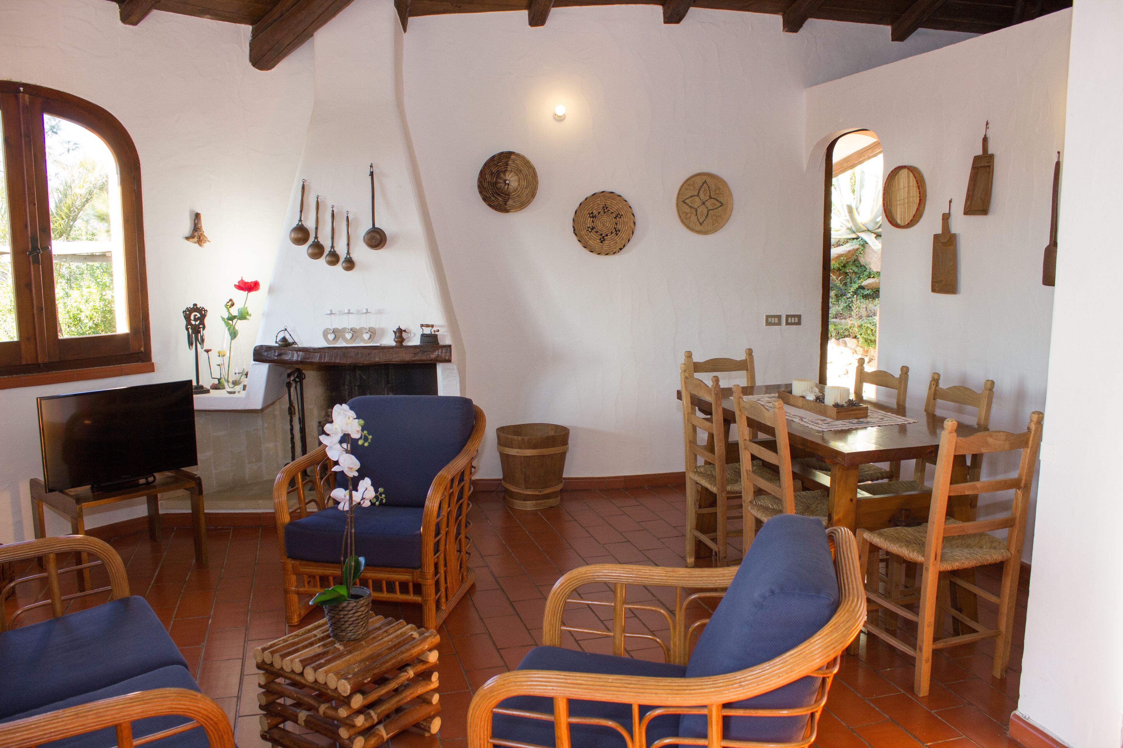 A room with a television, wicker furniture, a fireplace, and various wall decorations.