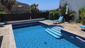 Una piscina con escalones, sillas de descanso y vista al océano.