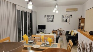 Una sala de estar moderna con comedor, televisor y obras de arte en las paredes.