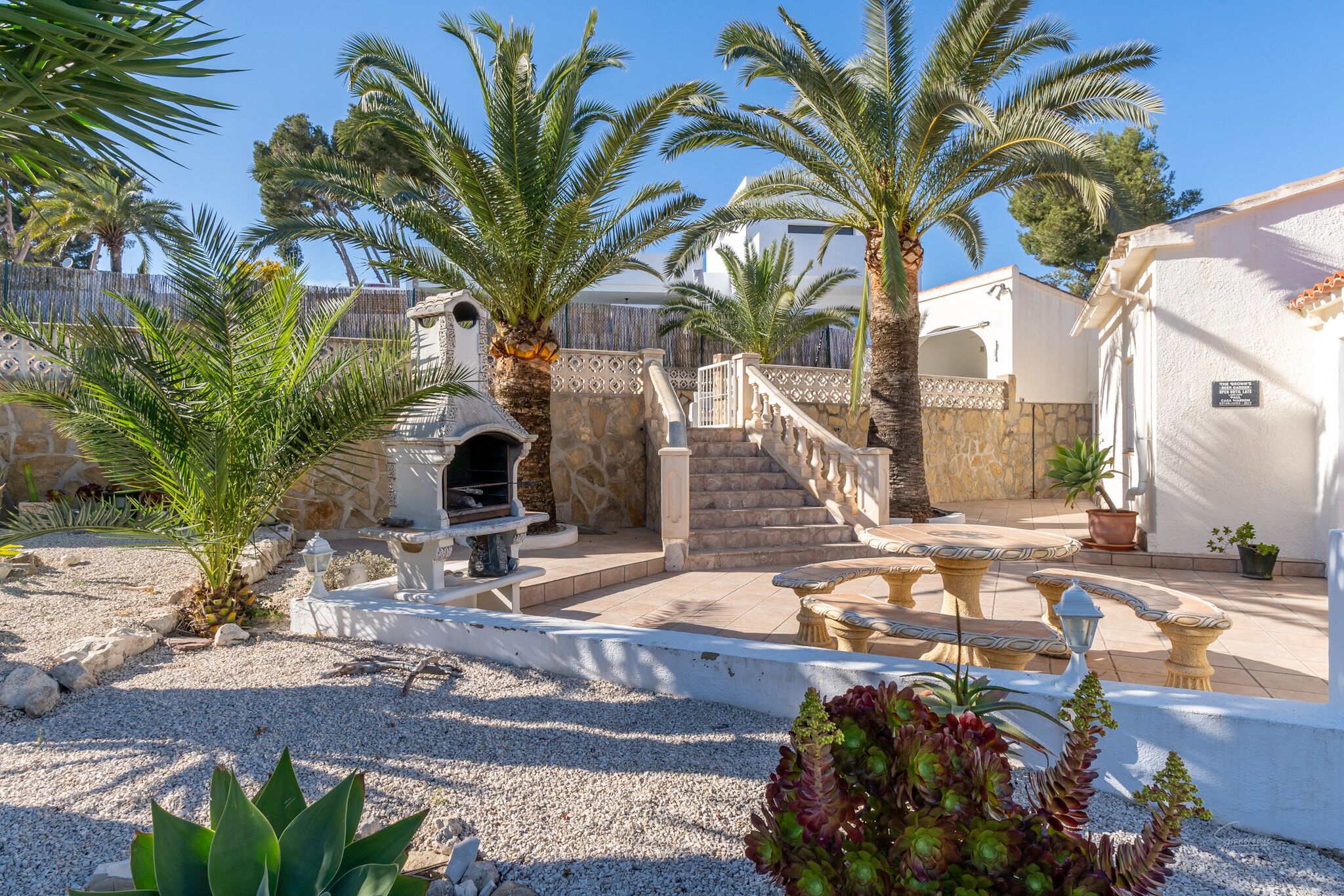 A courtyard with palm trees, a stone staircase, and outdoor seating.