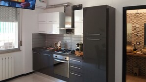 A modern kitchen with grey cabinets, a built-in oven, and a gas stove.