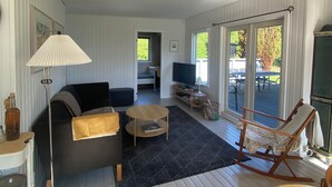 A spacious living room with a sofa, coffee table, and a rocking chair. There is a TV and a dining table with chairs. - Holiday house close to the beach  (Hundested)