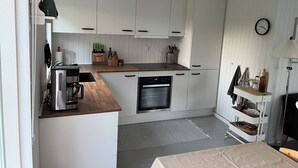 A modern kitchen with white cabinets, a built-in oven, and a coffee machine. - Holiday house close to the beach  (Hundested)