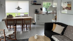 A modern living room with a dining area, kitchen, and a view of the outdoors. - Holiday house close to the beach  (Hundested)