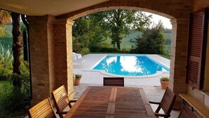 A covered outdoor area with a pool, wooden table, and chairs. - Very private, spacious, rural, detached villa with a pool, nestled between the sea and the mountains (Monte San Pietrangeli)