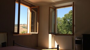 A bedroom with a bed, two windows, a radiator, and a dresser. - Very private, spacious, rural, detached villa with a pool, nestled between the sea and the mountains (Monte San Pietrangeli)