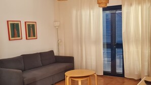 A living room with a sofa, a round wooden table, and two framed pictures on the wall. - Semi-detached Villa, 2 bedrooms, 2 bathrooms, private pool, WiFi, parking (Playa Blanca)