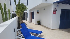 A courtyard with two blue lounge chairs, a cactus, and a sign for 'Villa Lanzarote.' - Semi-detached Villa, 2 bedrooms, 2 bathrooms, private pool, WiFi, parking (Playa Blanca)