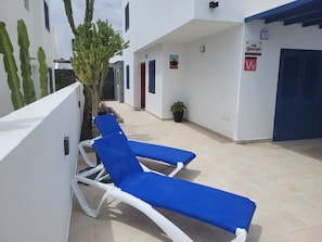 Sisäpiha, jossa on kaksi sinistä lepotuolia, kaktus ja kyltti, jossa lukee ”Villa Lanzarote”.
