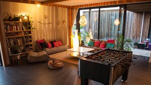 A cozy living room with a foosball table, a sofa, a bookshelf, and a large window with curtains. - BRIGHT 250m² ARCHITECT-DESIGNED VILLA OPEN TO THE OUTDOORS WITH PRIVATE POOL (Messanges)