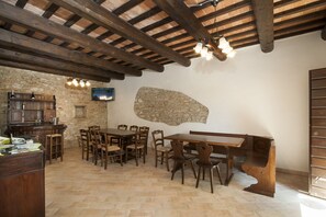 A rustic dining area with wooden furniture, stone walls, and a television mounted on the wall. - Colle di Pietra - Colle di PIetra (Cessapalombo)