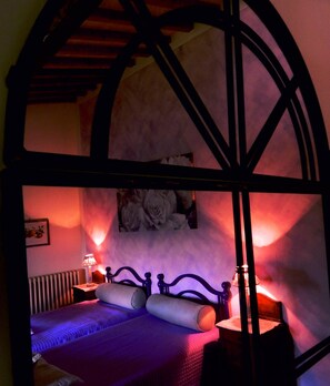 A bedroom with a bed, a nightstand, a lamp, and a wall-mounted picture of flowers. - Tuscan villa pool spa Siena Montepulciano Perugia Pienza Florence 2 hours from Rome (Cetona)