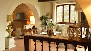 A cozy living room with a stone archway, a fireplace, comfortable seating, and a large window.