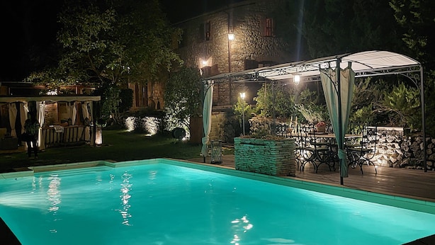 A swimming pool with a covered seating area and stone walls.