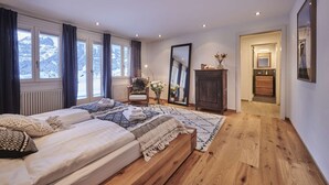 A bedroom with a bed, a chair, a mirror, and a dresser.