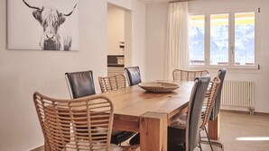 A dining area with a wooden table, wicker chairs, and a bull's head artwork on the wall.
