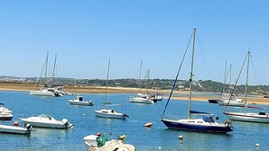 Un port de plaisance où sont amarrés différents types de bateaux, avec une eau calme et un ciel dégagé.