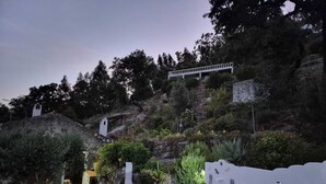 Un espace piscine agrémenté d’un mur blanc, d’une structure en pierre et d’un escalier menant au sommet d’une colline.