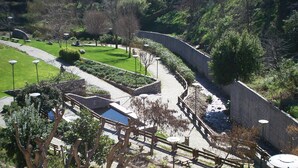 Un parc avec des sentiers, des bancs et un mur en pierre.