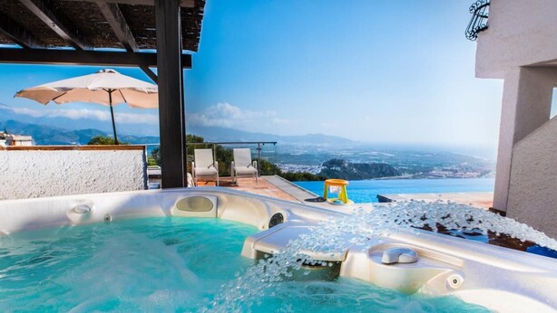 A hot tub with a clear view of the ocean and mountains in the background.