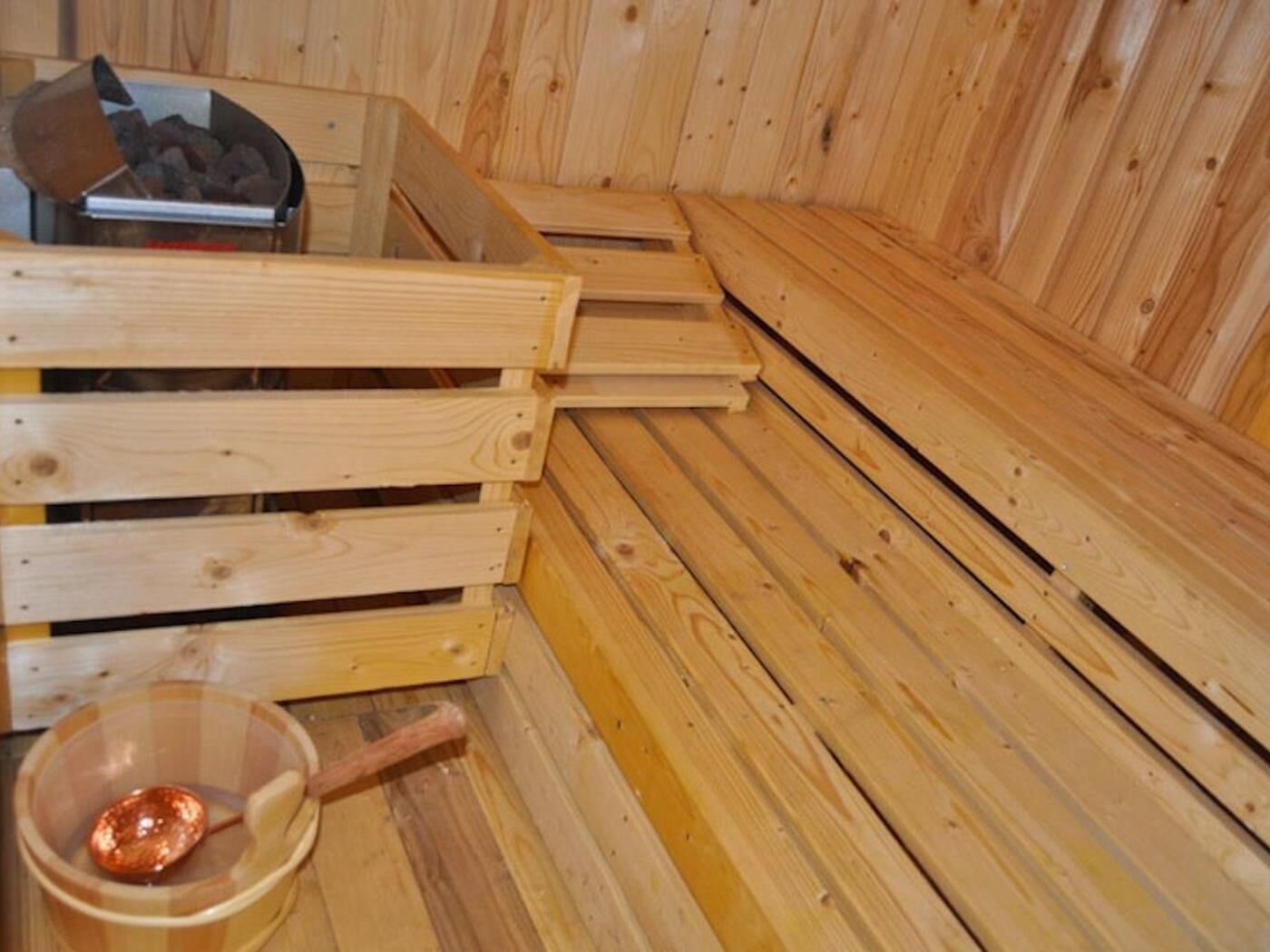 A wooden sauna with benches and a copper basin.
