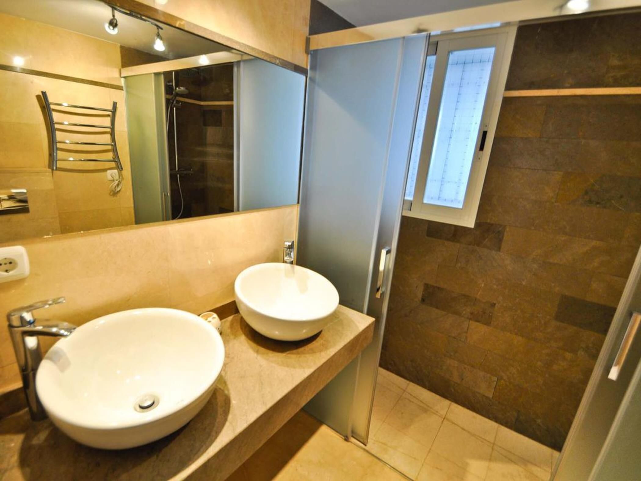 Een moderne badkamer met twee wastafels, een douche en een grote spiegel.
