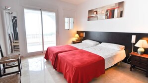 A hotel room with two beds, a balcony, and a view of the sea.