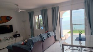Uma sala de estar moderna com sofá, televisão, ventilador de teto e área de jantar com cadeiras e mesa.
