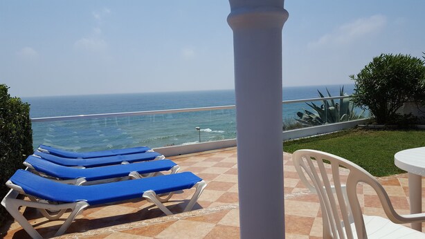 Terraço com cadeiras de descanso azuis e vista para o oceano.