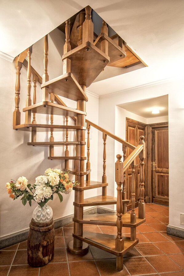 A wooden spiral staircase with a handrail, leading to an upper floor.