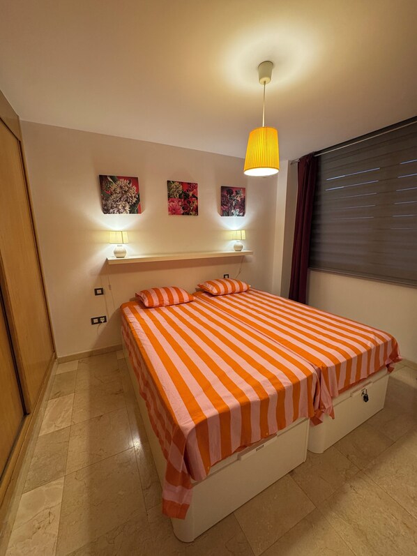 Une chambre à coucher avec un lit, une table de chevet, une lampe et des œuvres d’art murales.