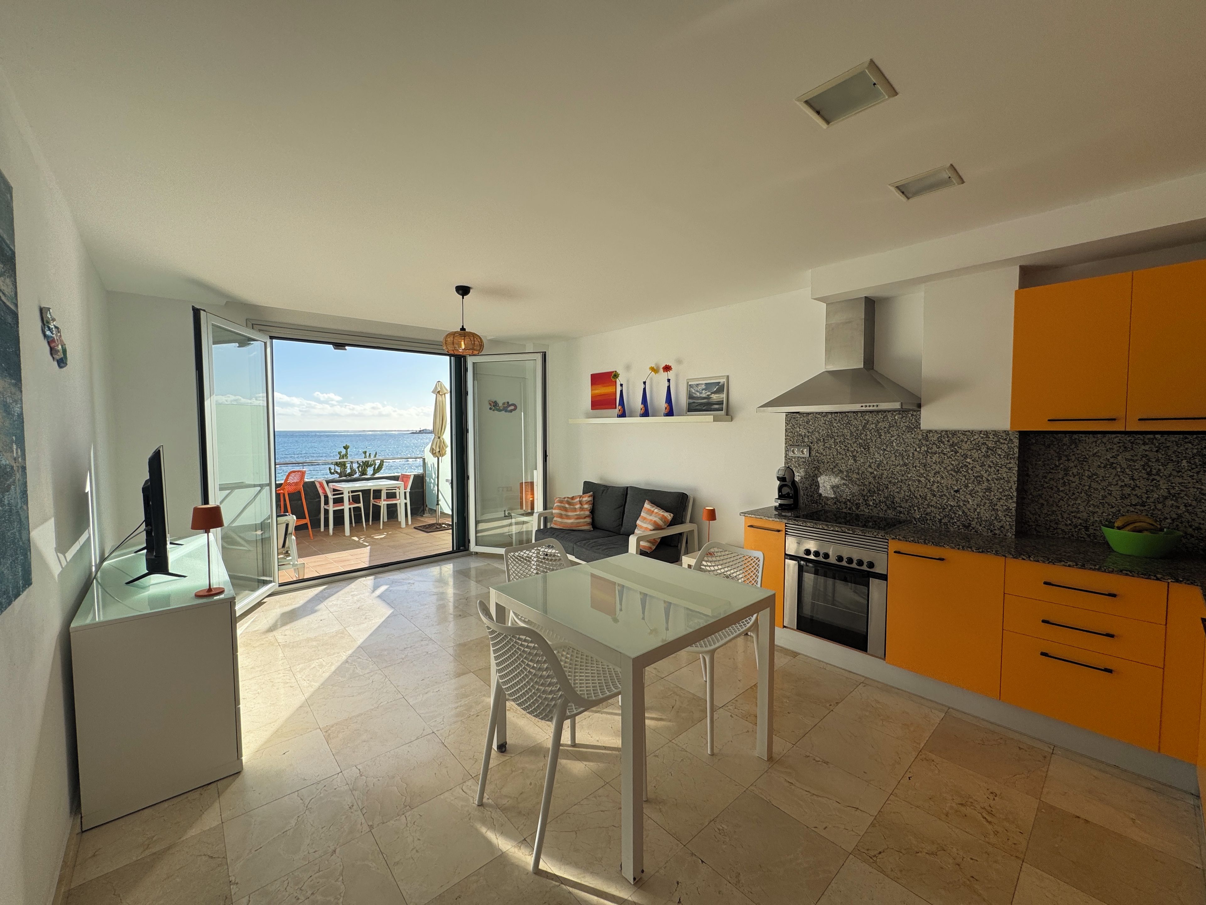 Eine moderne Küche mit Essbereich, Meerblick und einem Balkon.