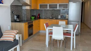 Cocina moderna con comedor, que incluye cafetera, microondas y refrigerador.