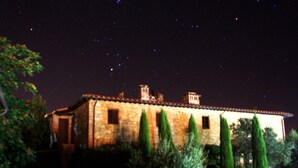 A historic building with a stone facade, several chimneys, and a courtyard with tall cypress trees. - Near San Gimignano Restored Air Conditioned Apartment with WiFi, Pool & Garden (San Gimignano Toscana)