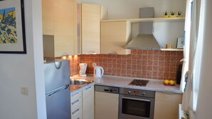 A compact kitchen with a dishwasher, oven, and a coffee maker. - Studio apartment Julia with balcony in Lapad (Dubrovnik)