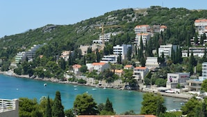 A coastal town with buildings on a hillside, a clear blue sea, and boats. - Studio apartment Julia with balcony in Lapad (Dubrovnik)