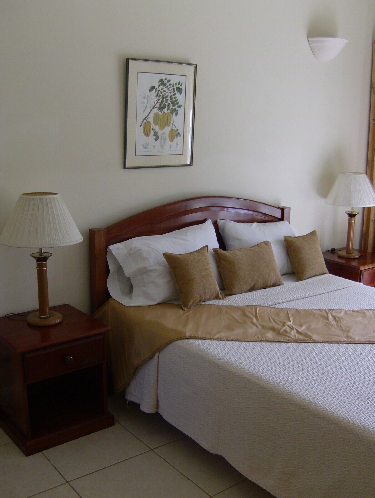 A neatly made bed with a wooden headboard, white and beige bedding, and two bedside lamps.