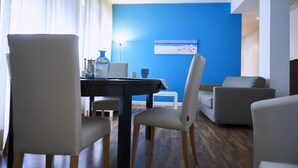 Ein modernes Wohnzimmer mit blauer Akzentwand, einem Esstisch mit Stühlen und einem Sofa.