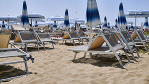 Ein Strand mit Reihen von Liegestühlen und Sonnenschirmen.