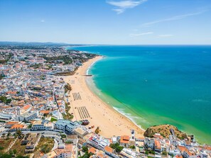 Eine Luftaufnahme einer Küstenstadt mit einem langen Sandstrand und einem klaren, blauen Meer.