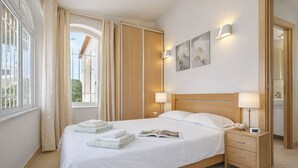 A hotel room with a bed, two bedside tables, a nightstand, a window with curtains, and artwork on the wall. - Beautiful 4 Bedroom Villa Silva, Private Pool, Close To The Strip And Old Town (Albufeira)