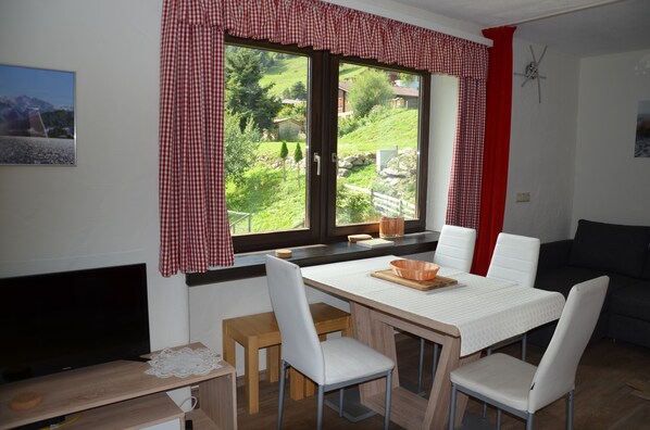 A dining area with a table, chairs, and a view of a green landscape through a window. - Recently renovated venue with last minute booking discounts through the summer. (Kaprun)