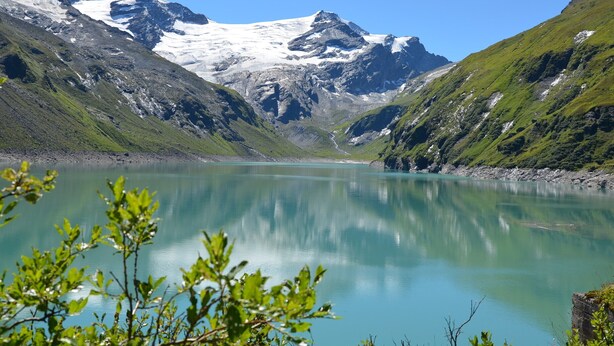 Un lago tranquilo rodeado de montañas con cumbres nevadas.