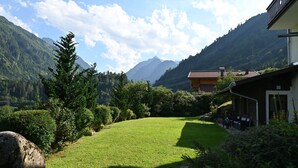 Un espacio cubierto de césped con un edificio y montañas al fondo.