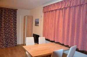 A dining area with a wooden table and white chairs, a wooden cabinet, and red and white checkered curtains. - Recently renovated venue with last minute booking discounts through the summer. (Kaprun)