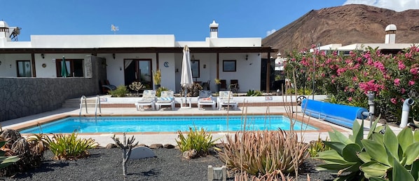 Een buitenzwembad, een verwarmd zwembad en ligstoelen