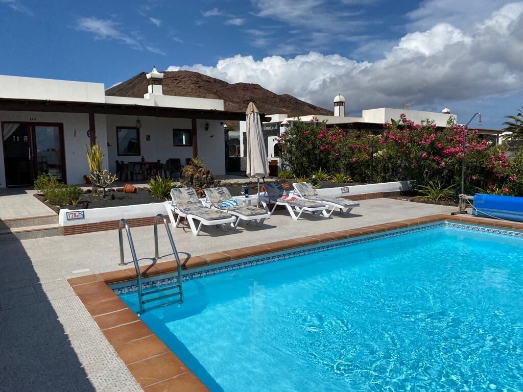 A swimming pool with lounge chairs and a small deck area.